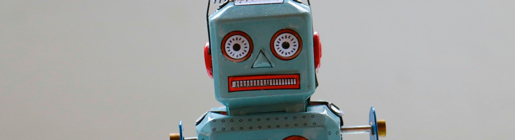 A pale blue vintage tin toy robot with a wind-up key at its side
