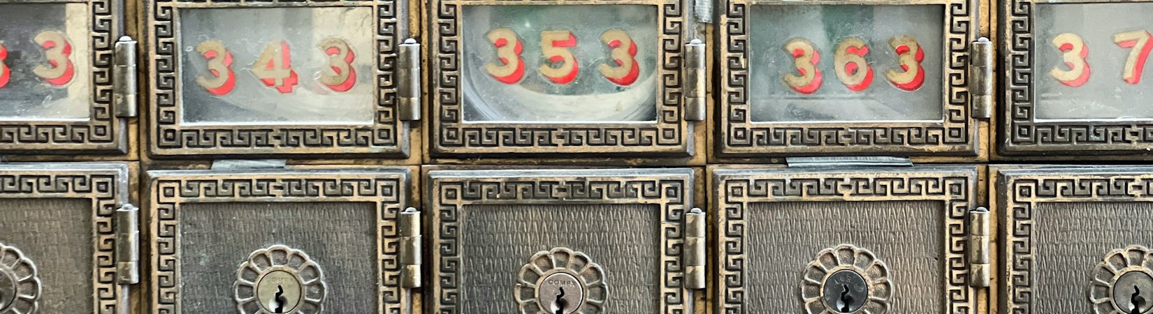 A wall of numbered brass post office boxes